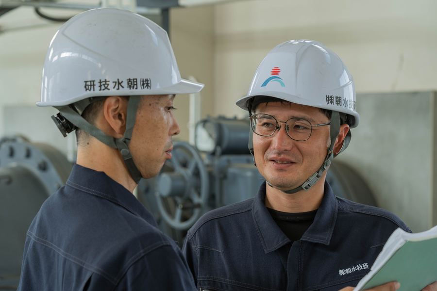 ヘルメット姿で打ち合わせる二人の技術者