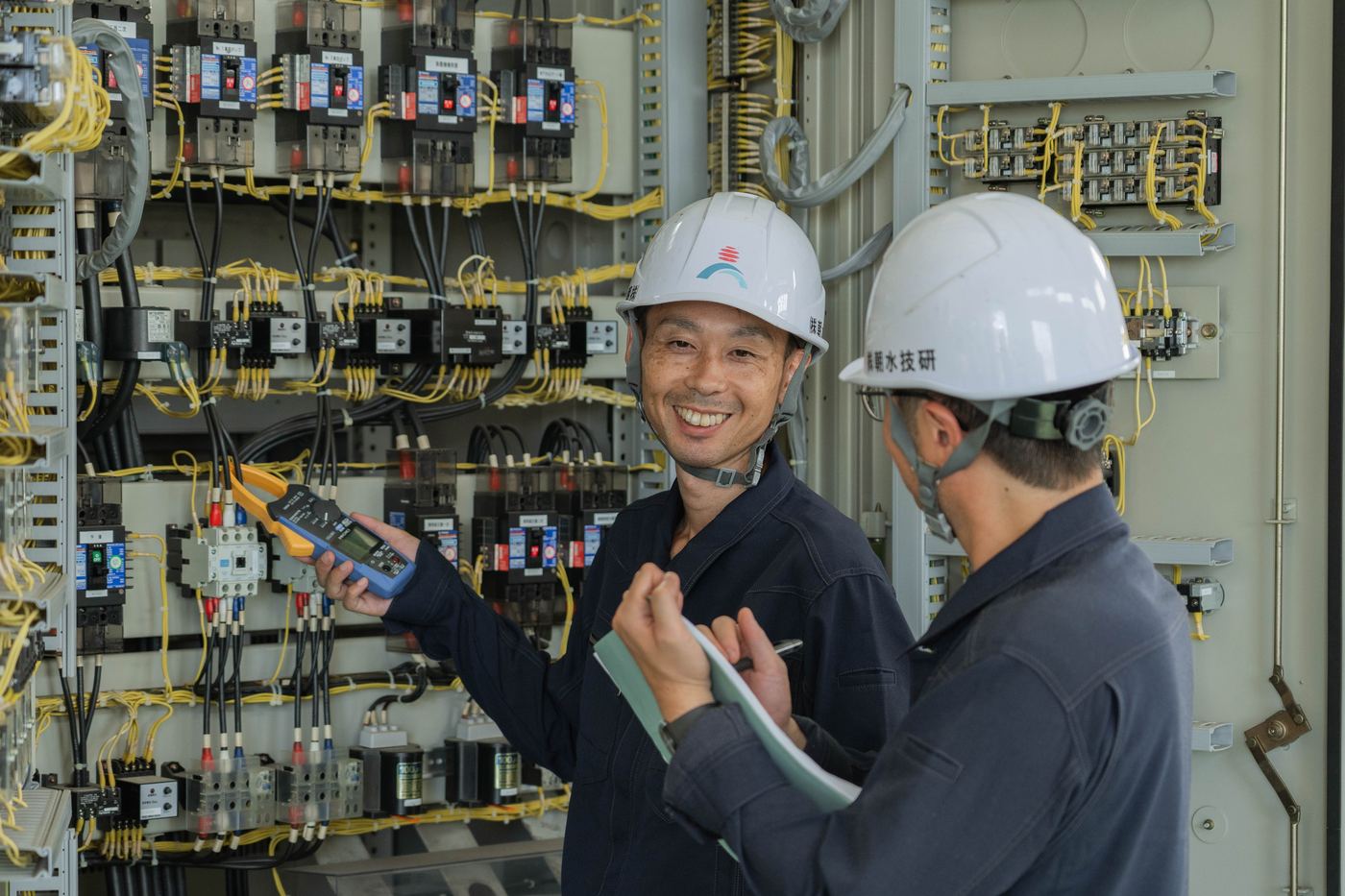 制御盤の電流を測定する技術者たち